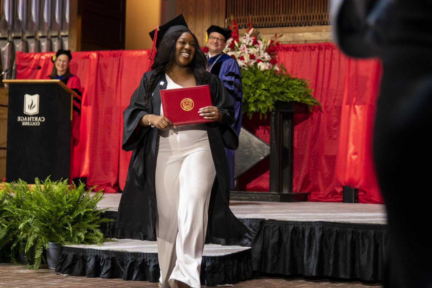 A 2023 Carthage College graduate beams as she leaves the Commencement stage after receiving her diploma from Carthage President John Swallow.